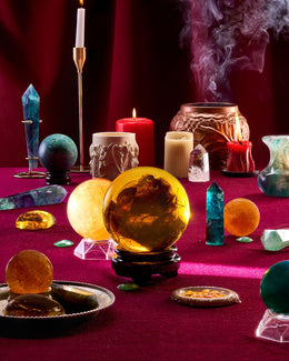 Witchcraft setup with crystal balls, candles, and smoky ambiance on a red surface.
